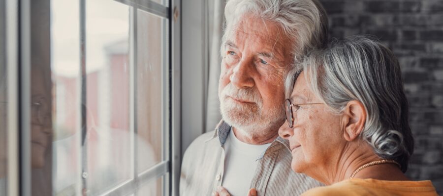 elderly couple looking out a window for symptoms of dementia