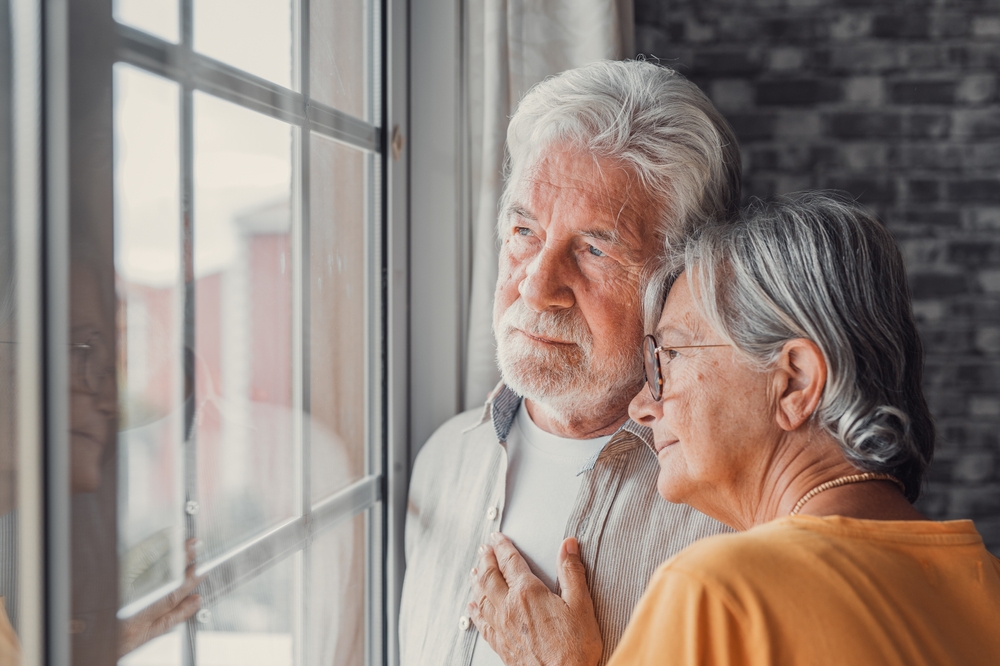 elderly couple looking out a window for symptoms of dementia
